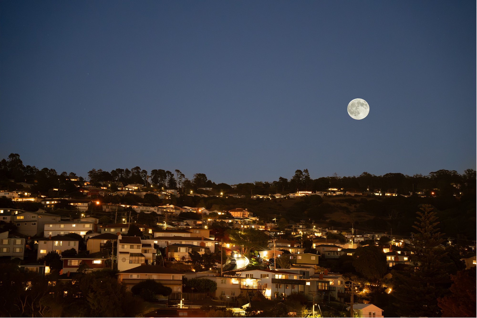 The full moon of the 2025 Mid-Autumn Festival rising over the hillside houses of El Cerrito, California, at dusk